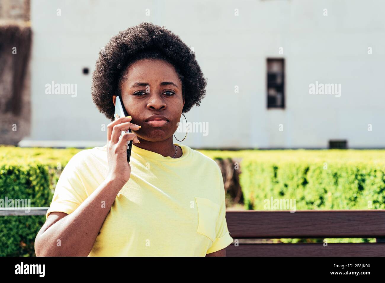 Portrait eines schwarzen Mädchens mit afrohaaren und Reifringen, die in einem städtischen Stadtraum anrufen. Stockfoto