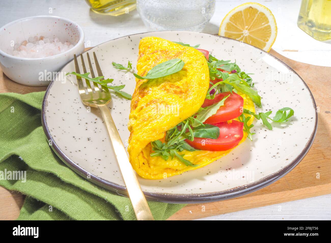 Frühling gesunde Ernährung Lebensmittelkonzept. Rühreier, gefülltes Omelett mit frischem Gemüse, Tomaten, Rucolla, Salat, auf weißem Hintergrund Platz zum Kopieren Stockfoto