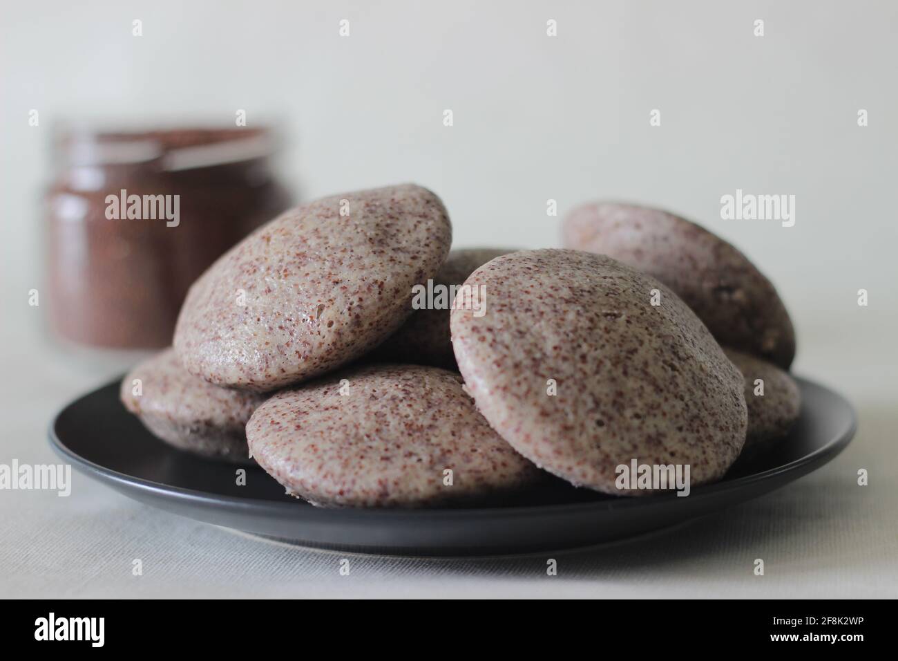 Gedünstete Kuchen mit Fingermilchmilch und geschältem schwarzem Gramm. Lokal bekannt als Ragi idli. Aufgenommen auf weißem Hintergrund. Stockfoto