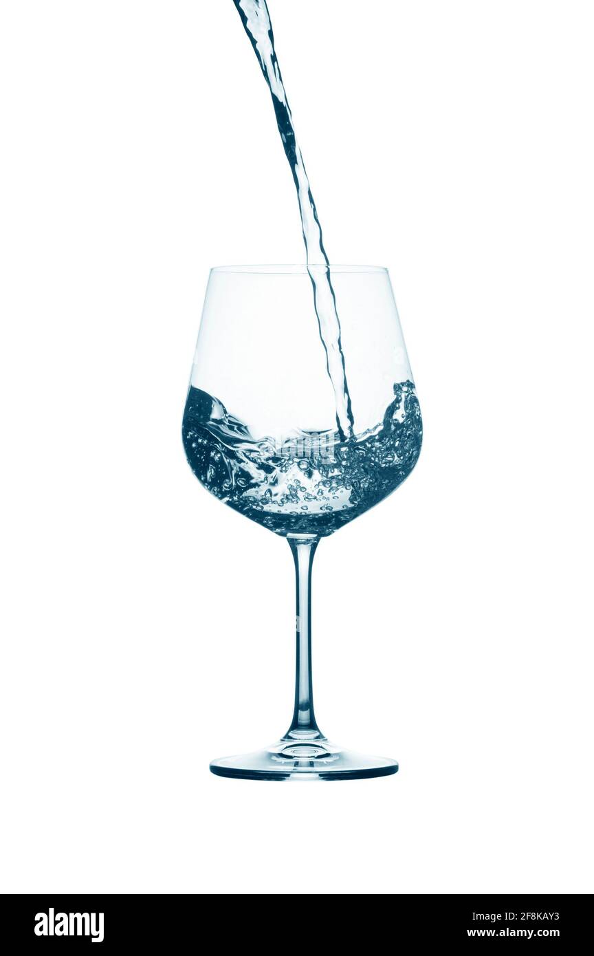 Wasser in ein Glas gießen, das auf weißem Hintergrund isoliert ist. Stockfoto