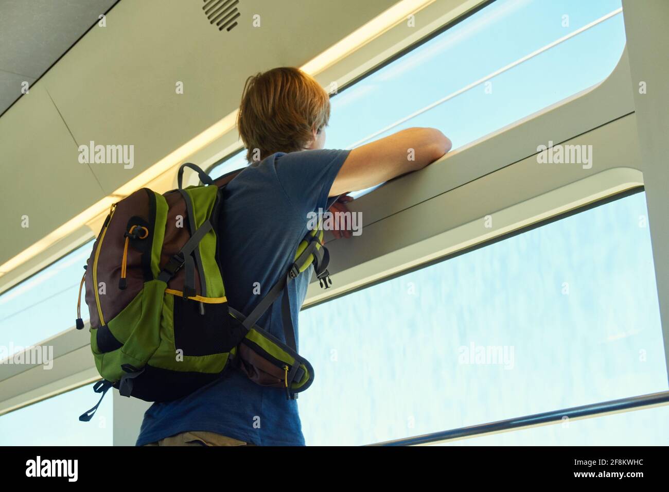 Mann mit Rucksack, der mit dem Zug fährt. Reisender auf der Straße, der aus dem Fenster schaut. Stockfoto