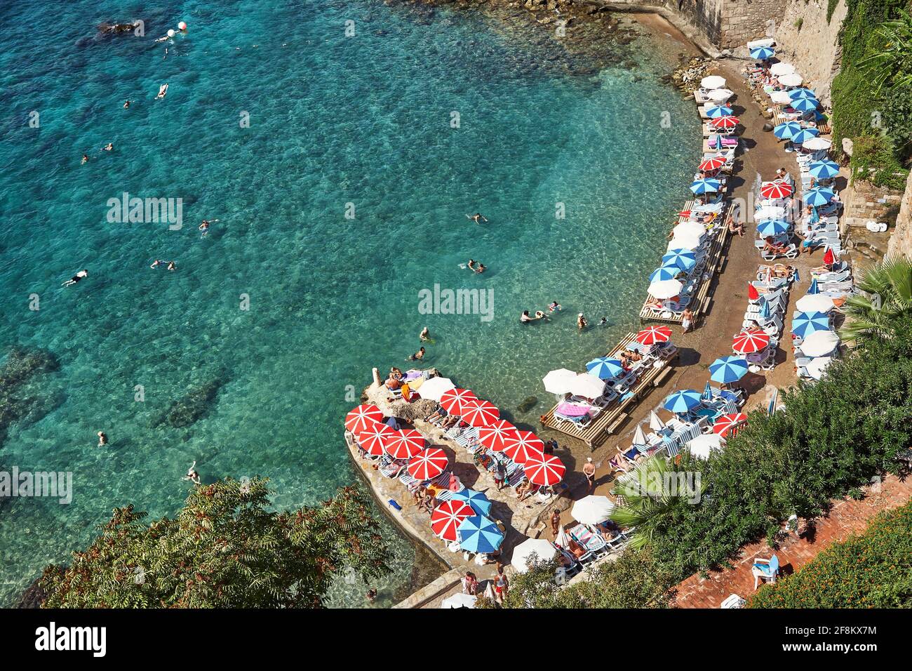 Strand mit Menschen im Urlaub in Liegestühlen und Sonnenschirmen in der Nähe des Wassers. Stockfoto