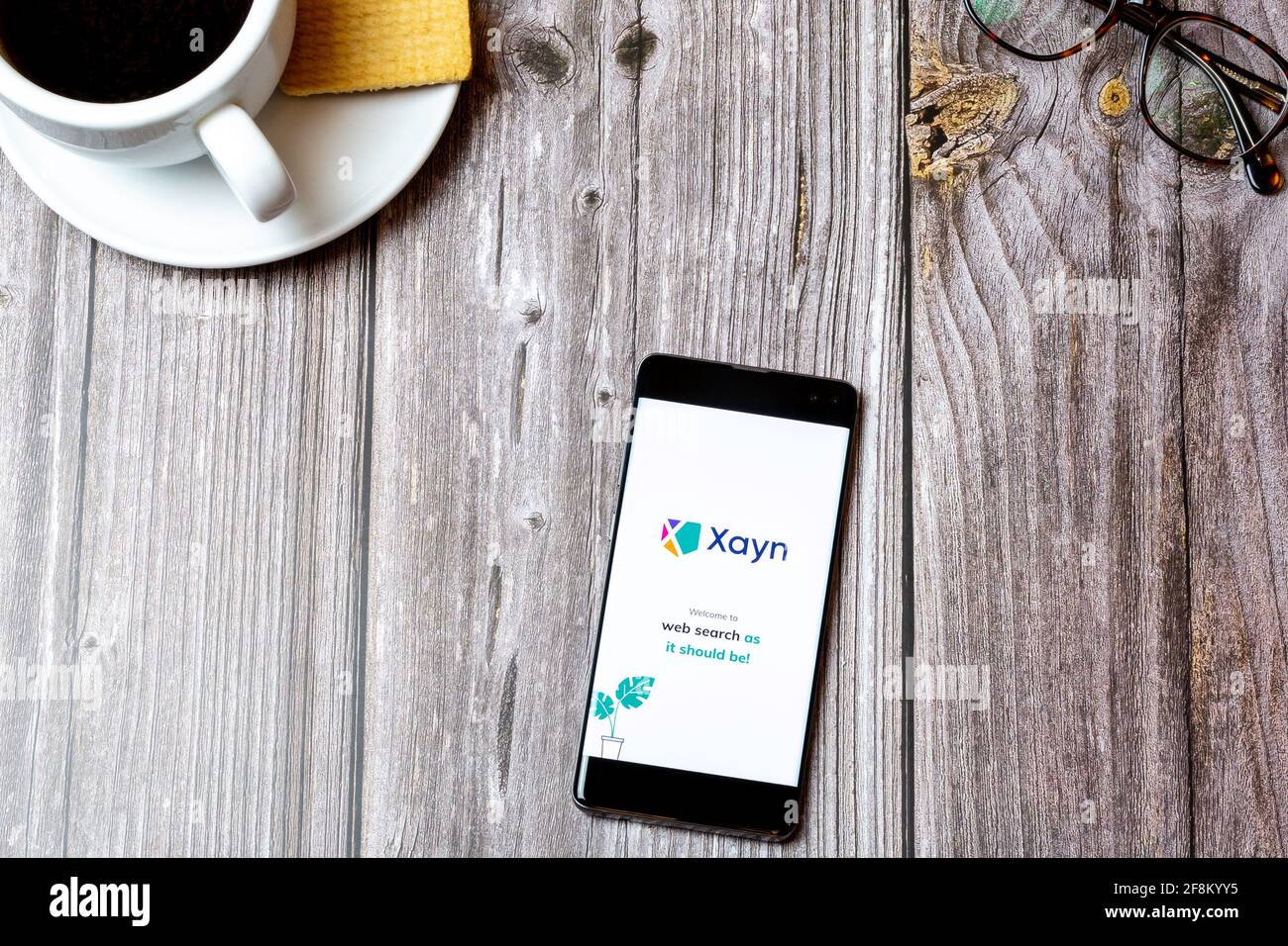 Ein Mobiltelefon oder Mobiltelefon, das auf einem Holzboden liegt Tabelle mit der Xayn-Websuchanwendung auf dem Bildschirm Stockfoto