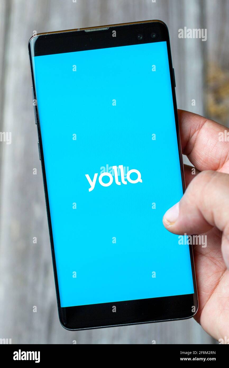 Ein Mobiltelefon oder Mobiltelefon, das in einem gehalten wird Hand zeigt die Yolla App auf dem Bildschirm Stockfoto