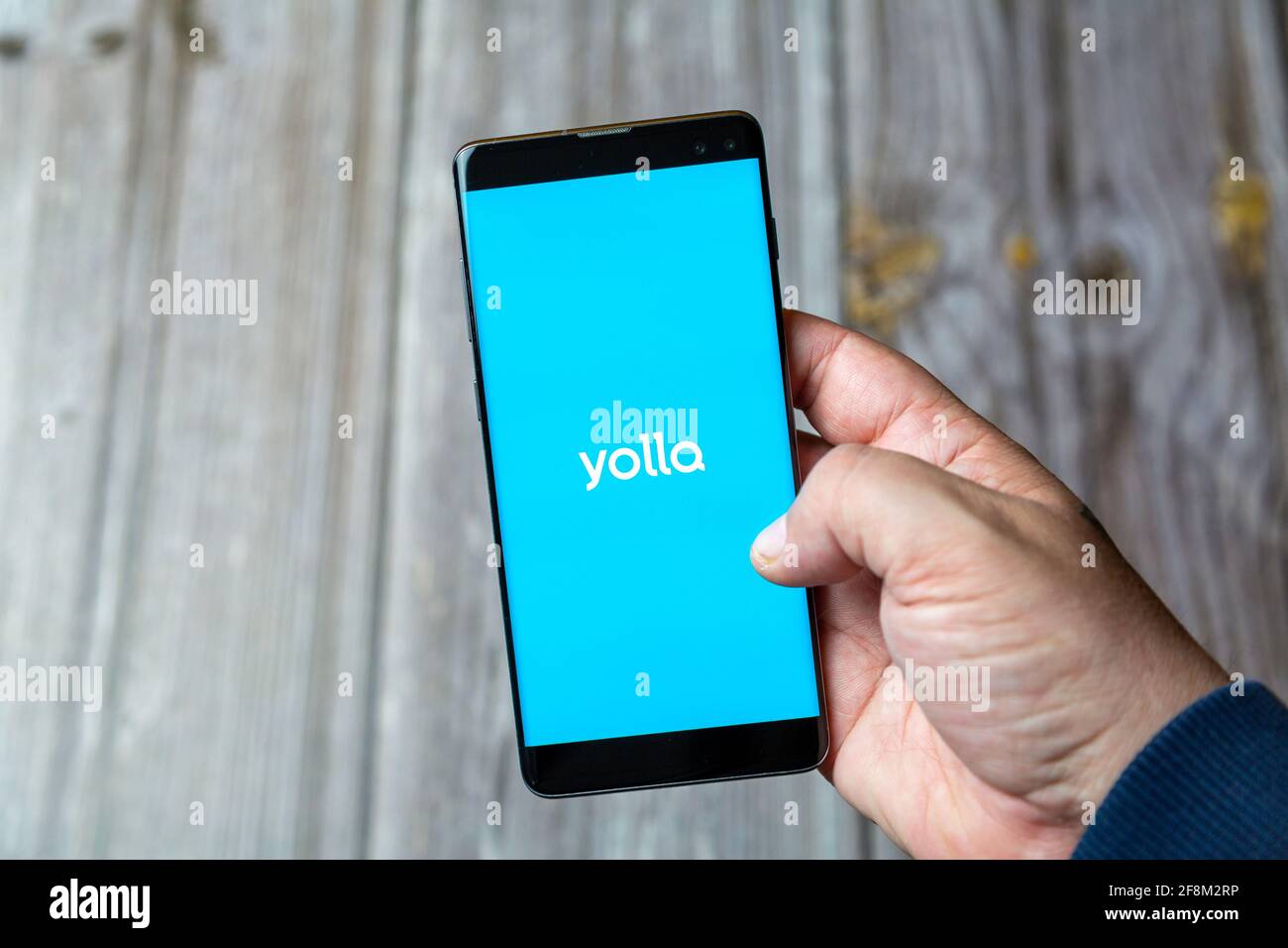 Ein Mobiltelefon oder Mobiltelefon, das in einem gehalten wird Hand zeigt die Yolla App auf dem Bildschirm Stockfoto