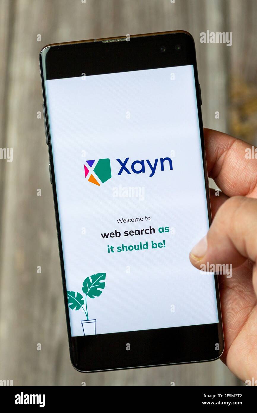 Ein Mobiltelefon oder Mobiltelefon, das in einem gehalten wird Hand, die die Xayn-Websuche-App auf dem Bildschirm zeigt Stockfoto