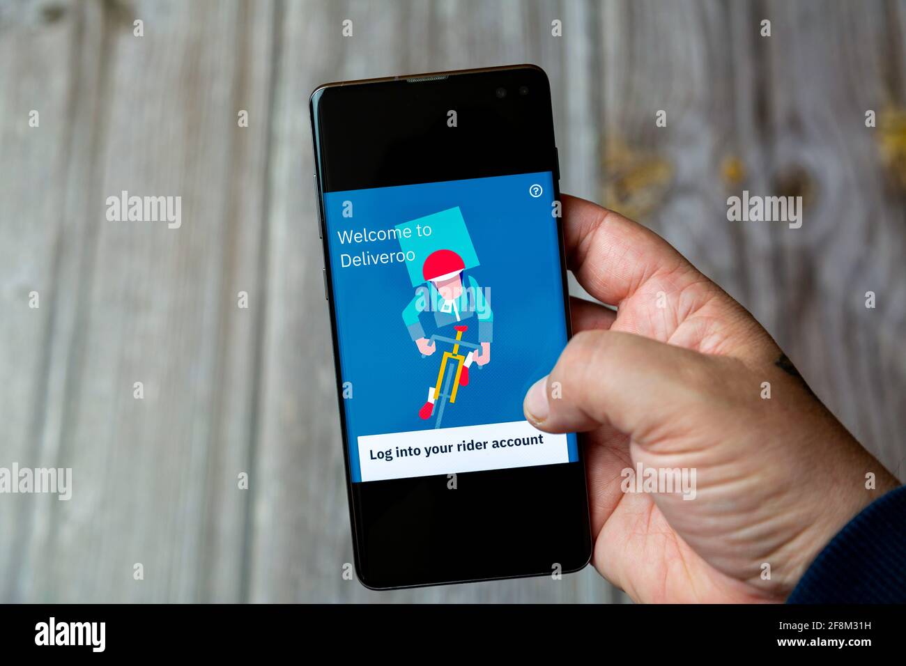 Ein Mobiltelefon oder Mobiltelefon, das in einem gehalten wird Hand zeigt die deliveroo Rider App auf dem Bildschirm Stockfoto