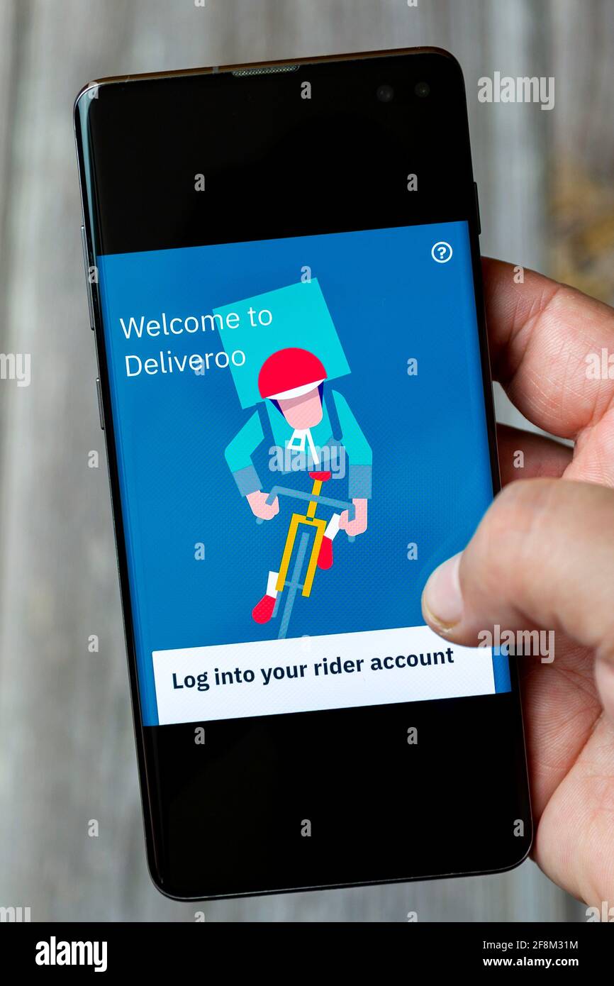 Ein Mobiltelefon oder Mobiltelefon, das in einem gehalten wird Hand zeigt die deliveroo Rider App auf dem Bildschirm Stockfoto