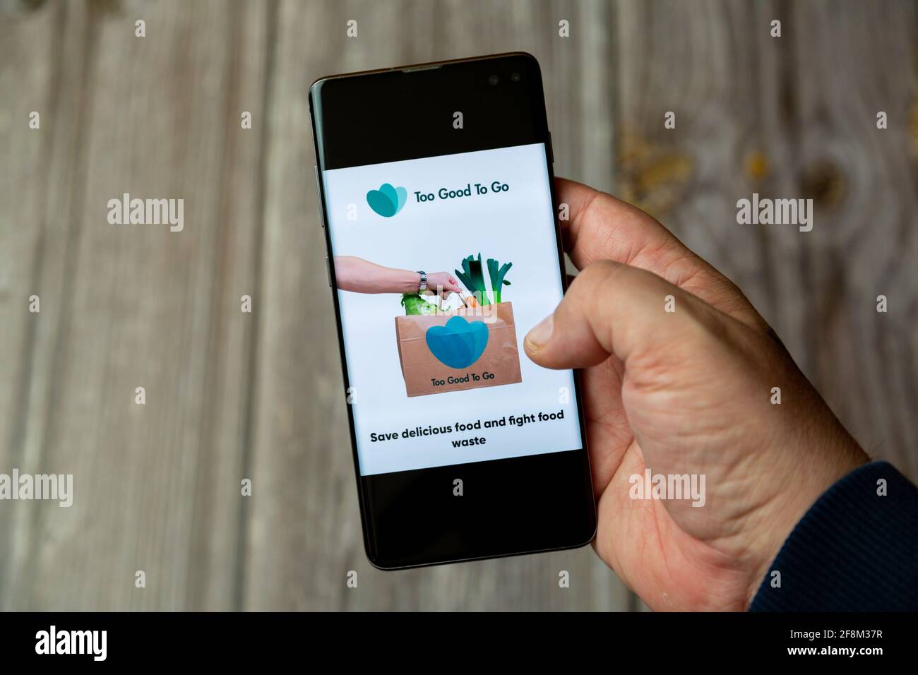 Ein Mobiltelefon oder Mobiltelefon, das in einem gehalten wird Hand zeigt die App „zu gut für unterwegs“ auf dem Bildschirm Stockfoto