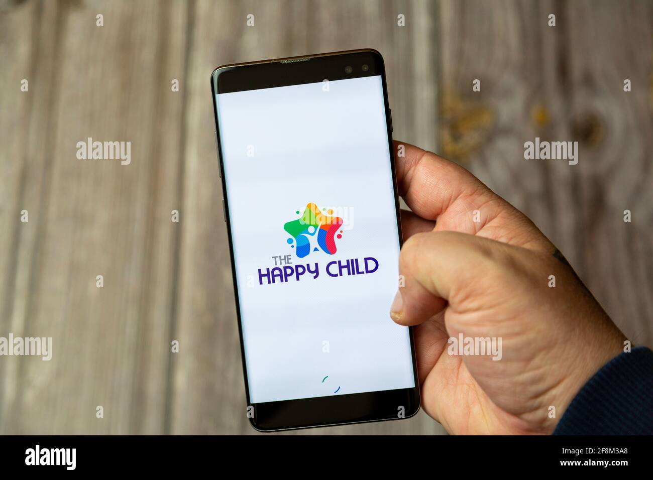 Ein Mobiltelefon oder Mobiltelefon, das in einem gehalten wird Hand zeigt die Happy Child App auf dem Bildschirm Stockfoto