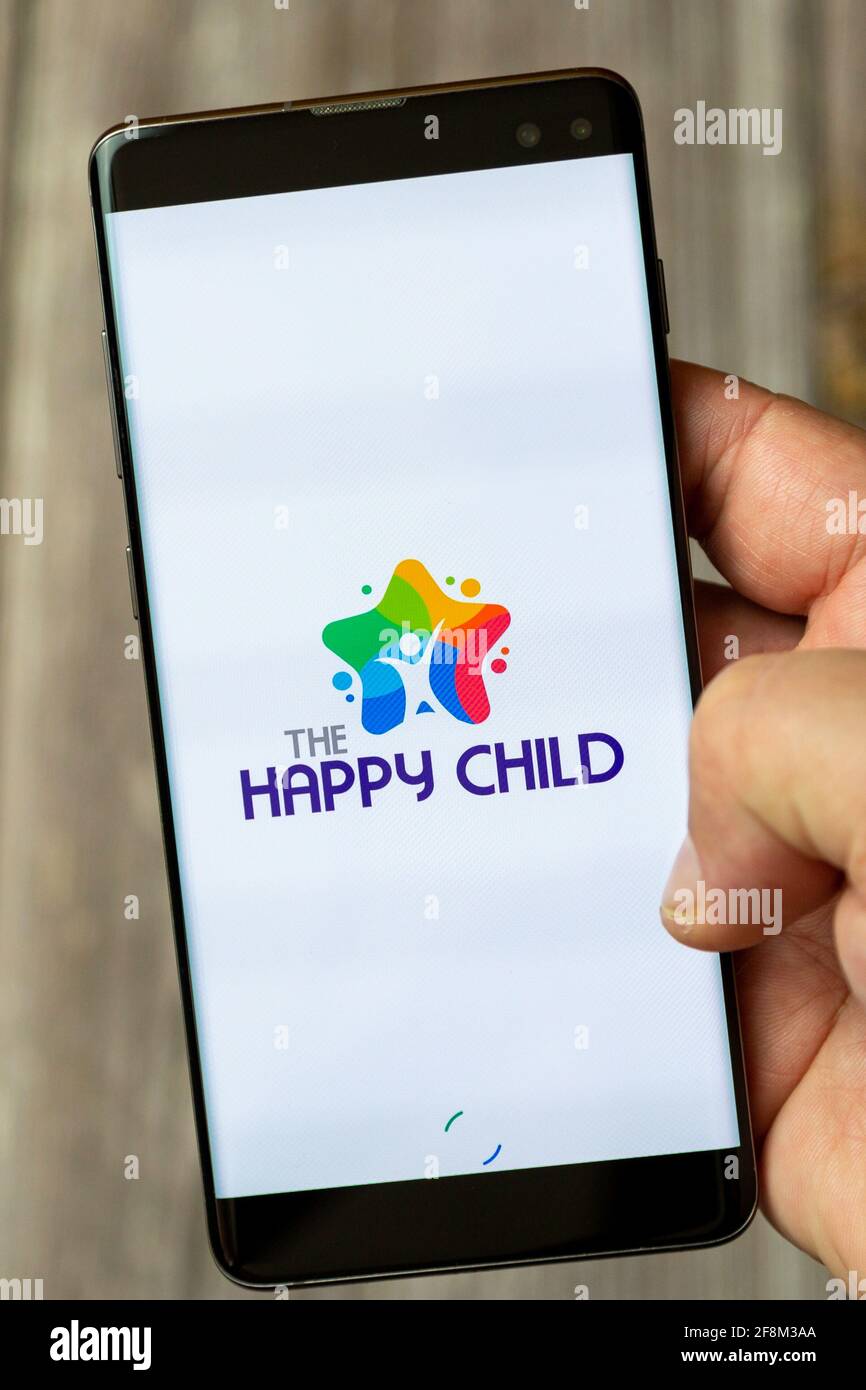 Ein Mobiltelefon oder Mobiltelefon, das in einem gehalten wird Hand zeigt die Happy Child App auf dem Bildschirm Stockfoto