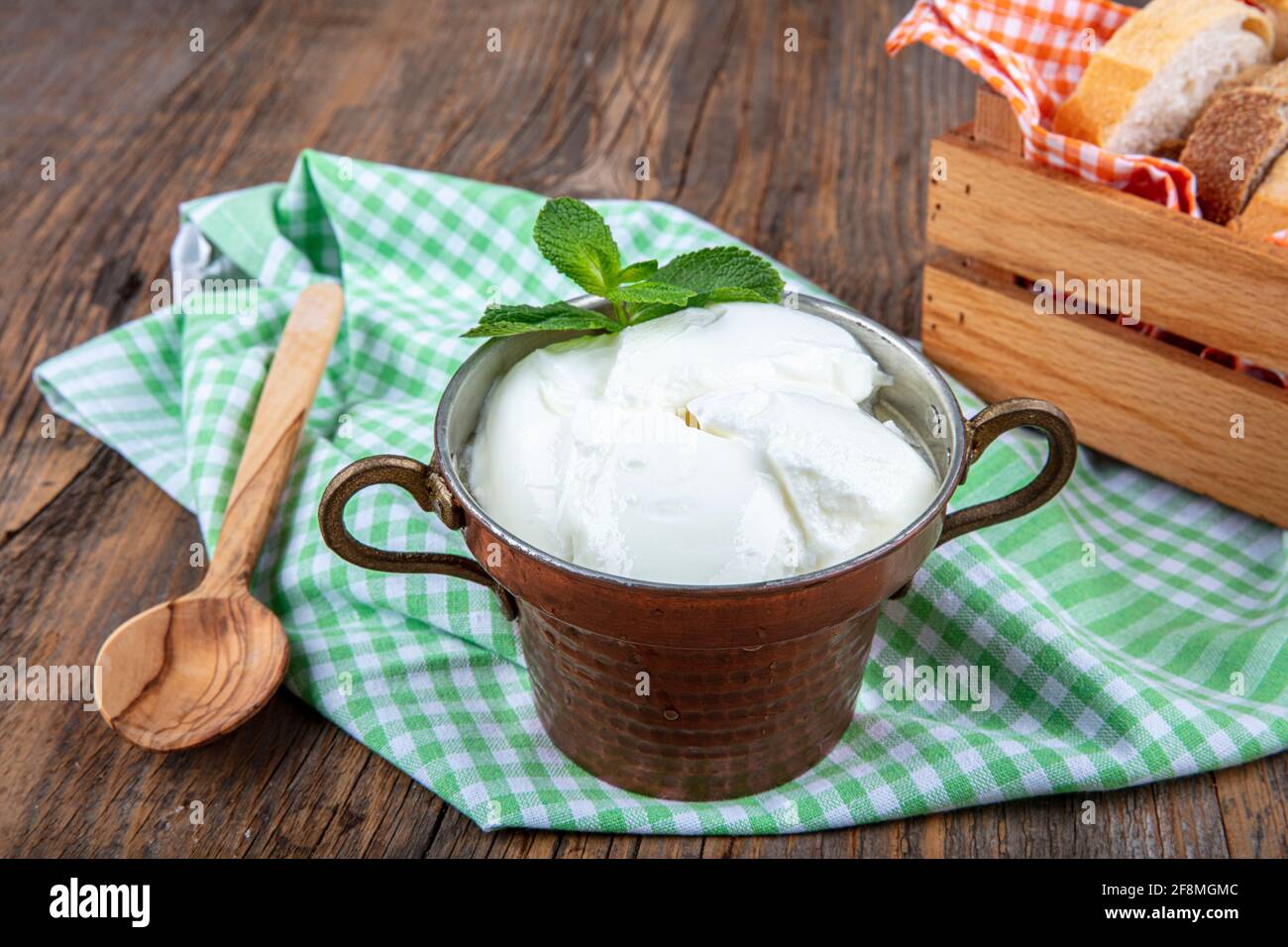 Wasser Büffeljoghurt fermentiert in Kupferschüssel. Hausgemachter Joghurt in Schüssel auf Holztisch, Draufsicht, Kopierplatz. Bio-reiner griechischer Joghurt für gesundes b Stockfoto