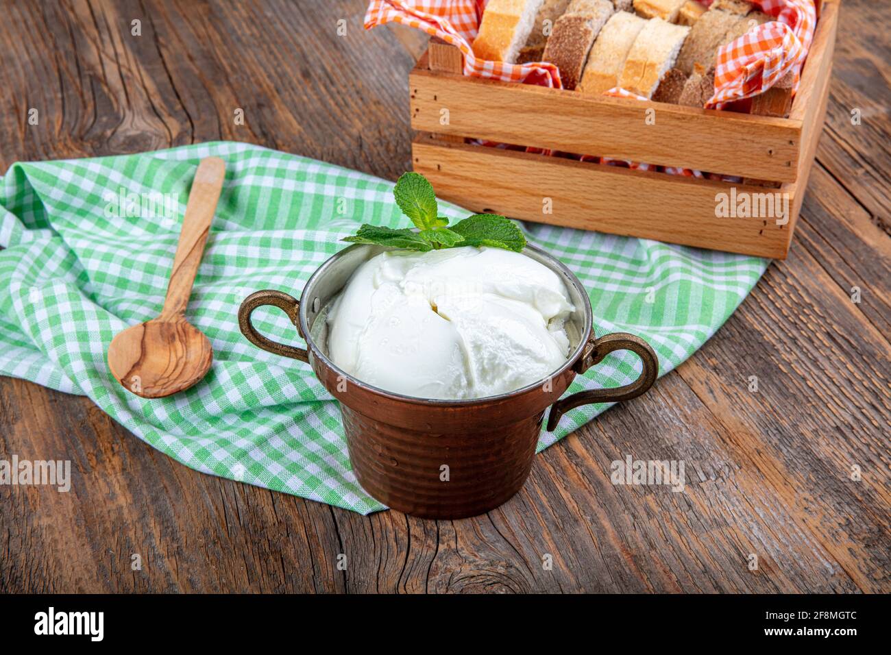 Wasser Büffeljoghurt fermentiert in Kupferschüssel. Hausgemachter Joghurt in Schüssel auf Holztisch, Draufsicht, Kopierplatz. Bio-reiner griechischer Joghurt für gesundes b Stockfoto