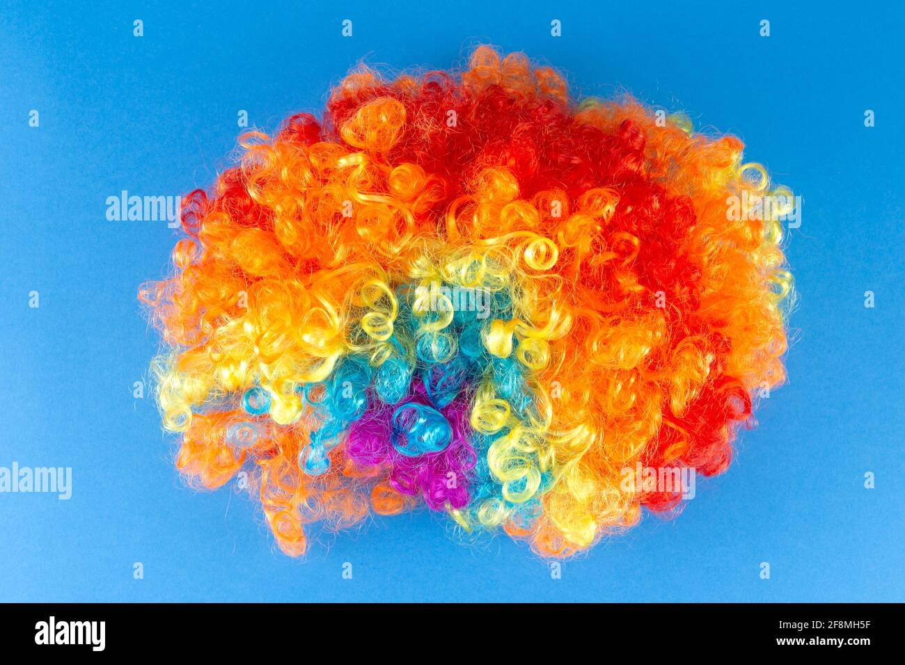Lustige Party Konzept Regenbogen Clown Perücke flauschig Afro Synthetisch Cosplay Anime Fancy Wigs Festlichen Hintergrund Stockfoto