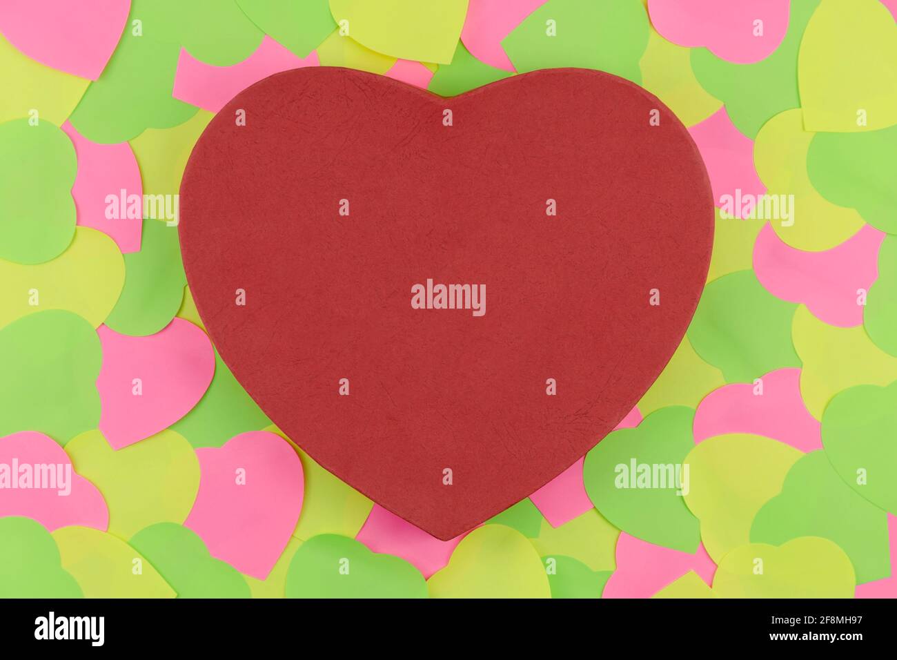 Rote Herzform mit Textur auf Neon-Haftnotizen in Herzform auf blauem Hintergrund. Love in Valentine's Day Date Konzept Stockfoto