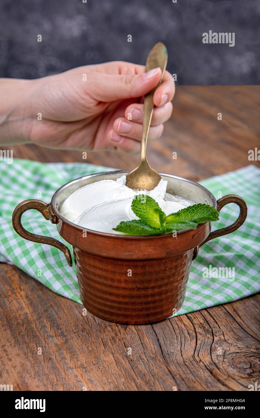 Wasser Büffeljoghurt fermentiert in Kupferschüssel. Hausgemachter Joghurt in Schüssel auf Holztisch, Draufsicht, Kopierplatz. Bio-reiner griechischer Joghurt für gesundes b Stockfoto