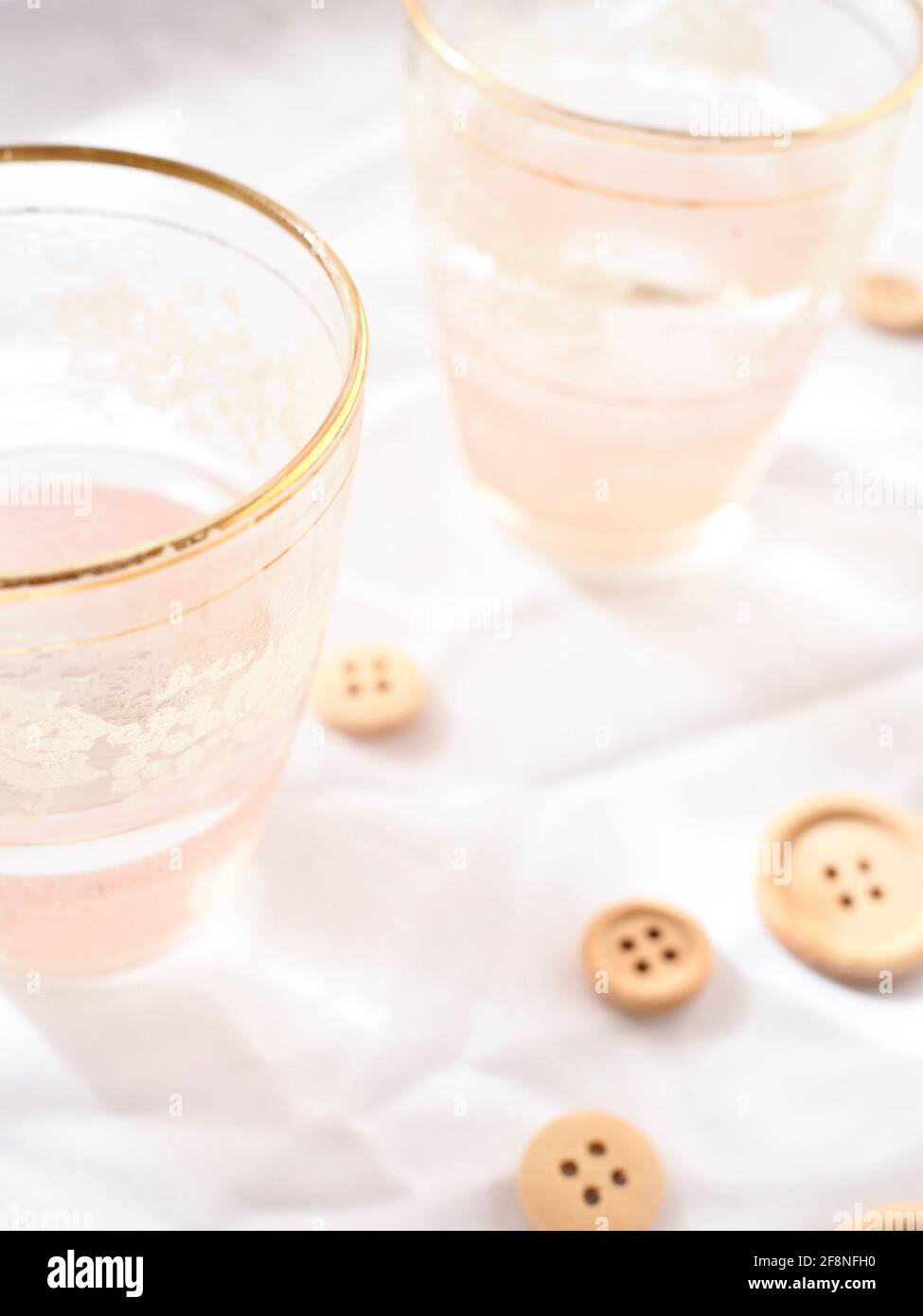 Hübsche rosa Gläser und Holzknöpfe auf hellweißem Hintergrund. Stockfoto