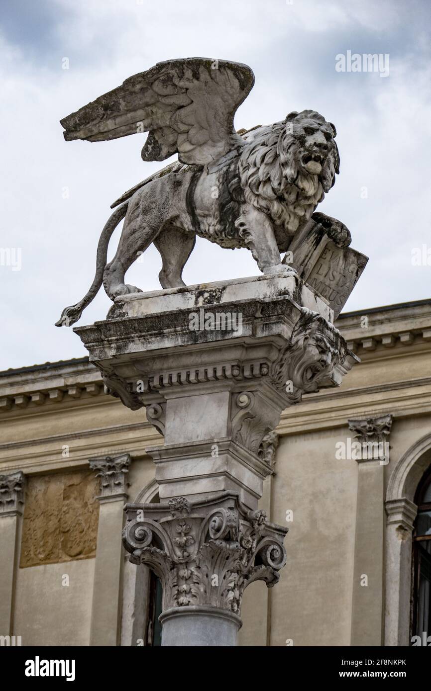 Vertikale Aufnahme eines geflügelten Löwen auf der Säule, die zeigt Ein Buch im Hintergrund eines Gebäudes in Italien Stockfoto
