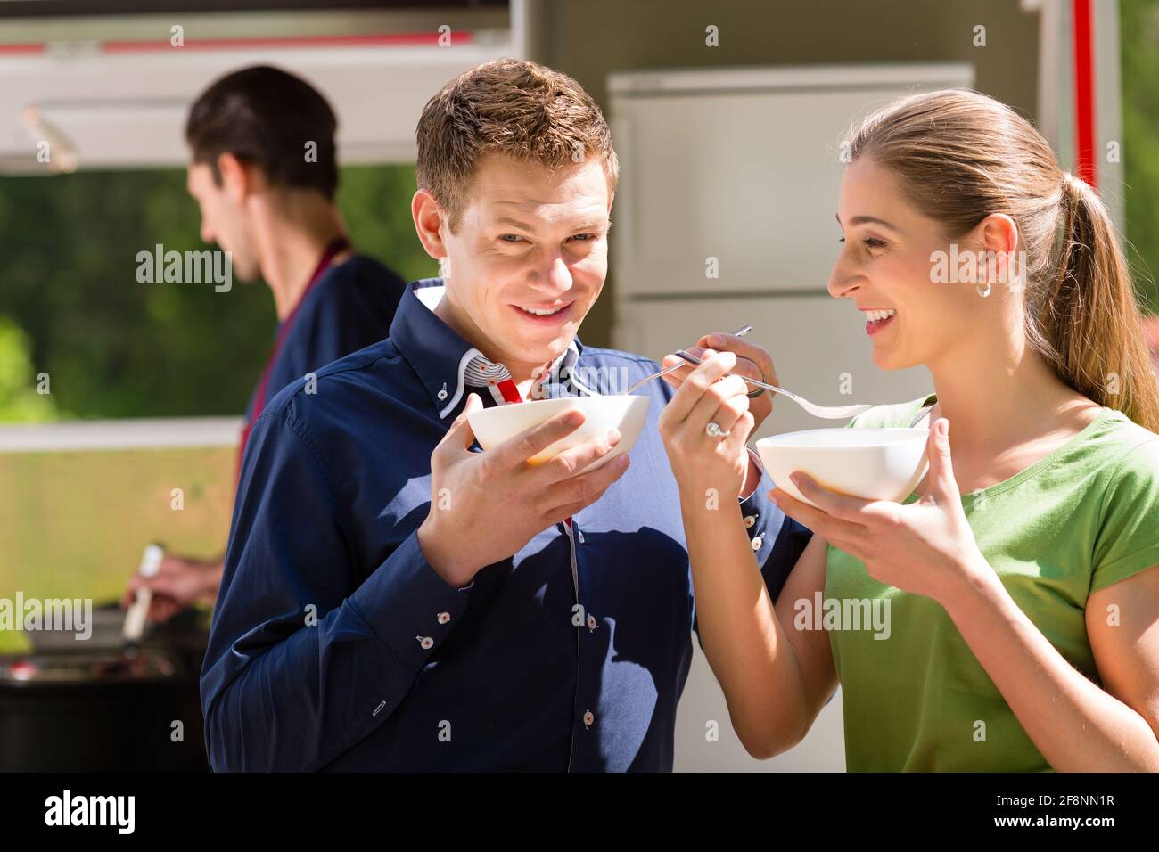 Ein junges Paar – Mann und Frau – nimmt eine Nudelsuppe auf einem Stand, es schmeckt offensichtlich gut Stockfoto