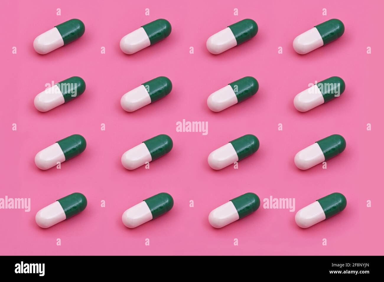 Weiße grüne Kapsel Pharmazeutische Medizin Tablette auf einem rosa Hintergrund, Medizin kreative Konzepte Minimal Stil mit bunten Papier Hintergrund Stockfoto