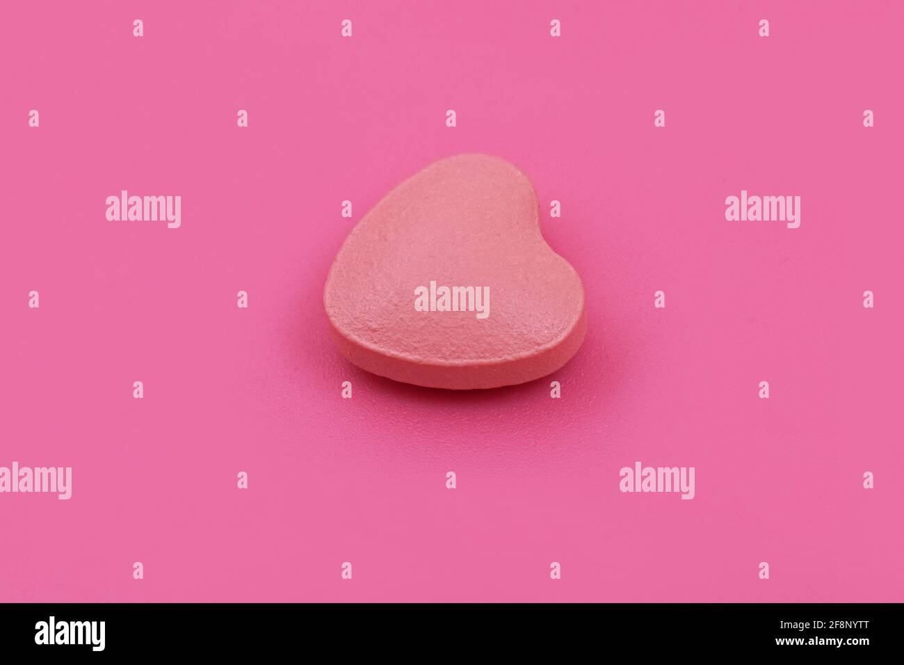 Herzform Pharmazeutische Medizin Tablette auf rosa Hintergrund, flache Lay Copy Raum Medizin Konzepte Baby rosa Farbe Hintergrund Stockfoto