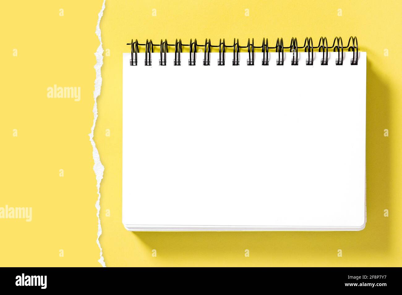 Spiralnotepad Buchmockup und zerrissene Papierumrandung zur Präsentation Ihres Designs. Gelber Hintergrund Stockfoto