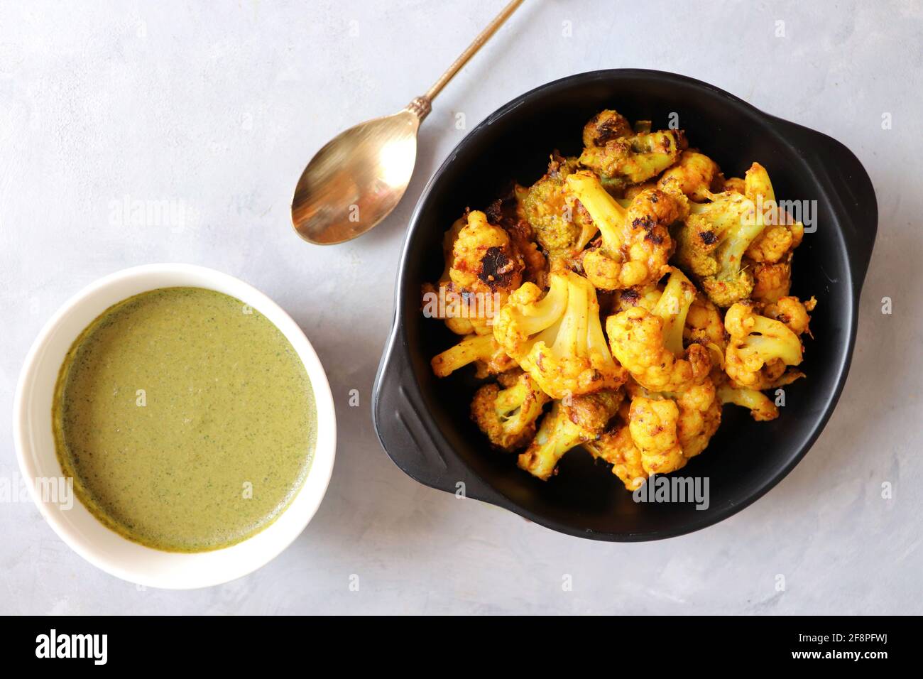 Gobi oder Gobhi Tandoori. Masala gerösteter Blumenkohl ist ein beliebtes indisches vegetarisches Vorspeise Gericht serviert mit Minze und Koriander Chutney. Stockfoto