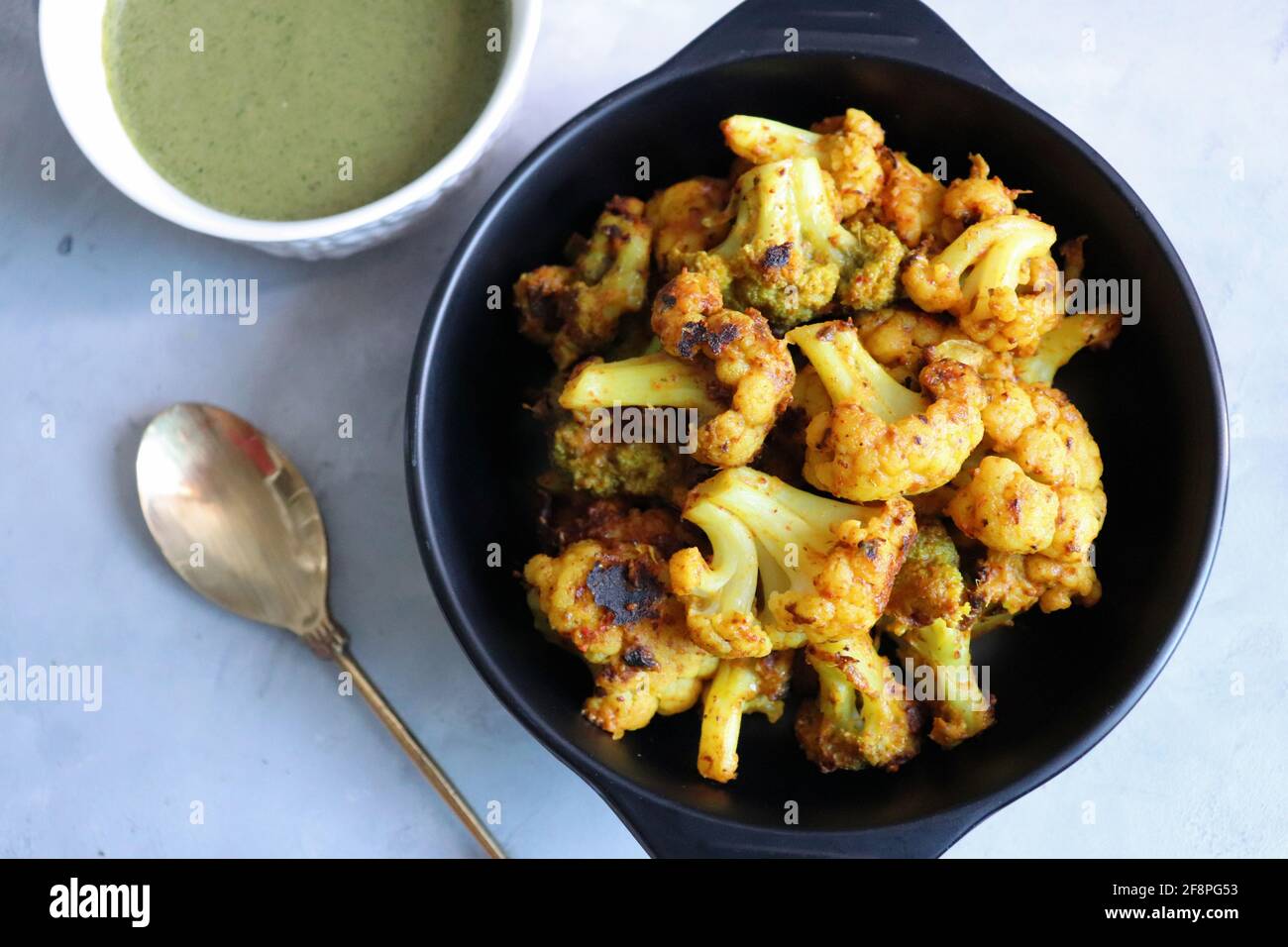Gobi oder Gobhi Tandoori. Masala gerösteter Blumenkohl ist ein beliebtes indisches vegetarisches Vorspeise Gericht serviert mit Minze und Koriander Chutney. Stockfoto