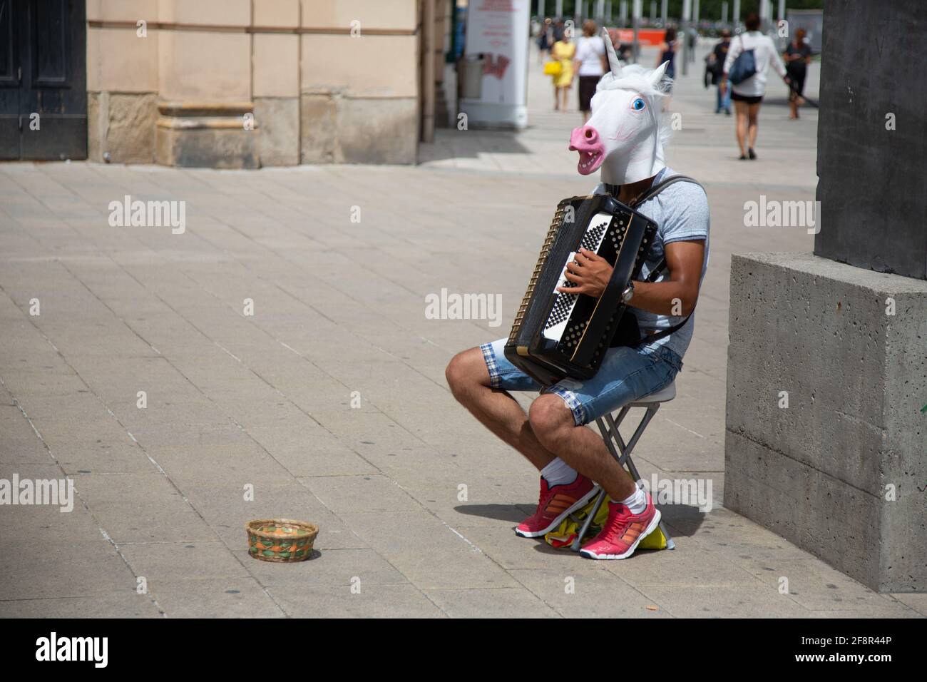 In Wien spielt ein Akkordeonist, der bizarre Einhorn-Kopfbedeckungen trägt, Busker Stockfoto