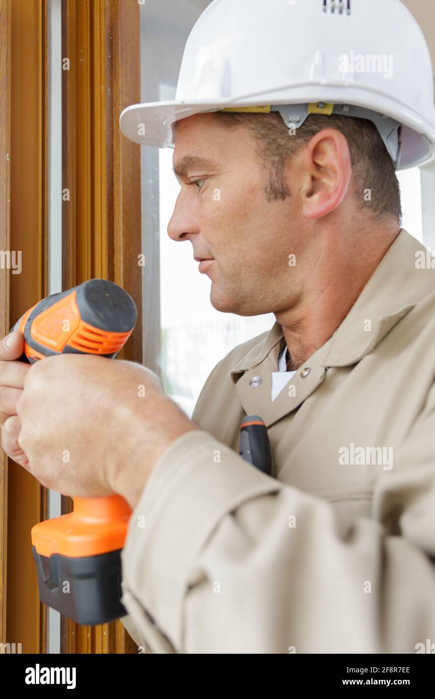 Handwerker treibt die Schraube in den Holzrahmen Stockfoto