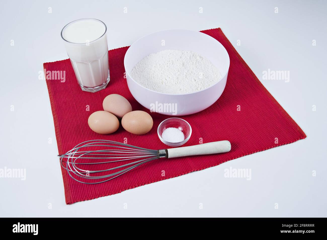 Zutaten für einen Pfannkuchenteig auf einer roten Matte Stockfoto