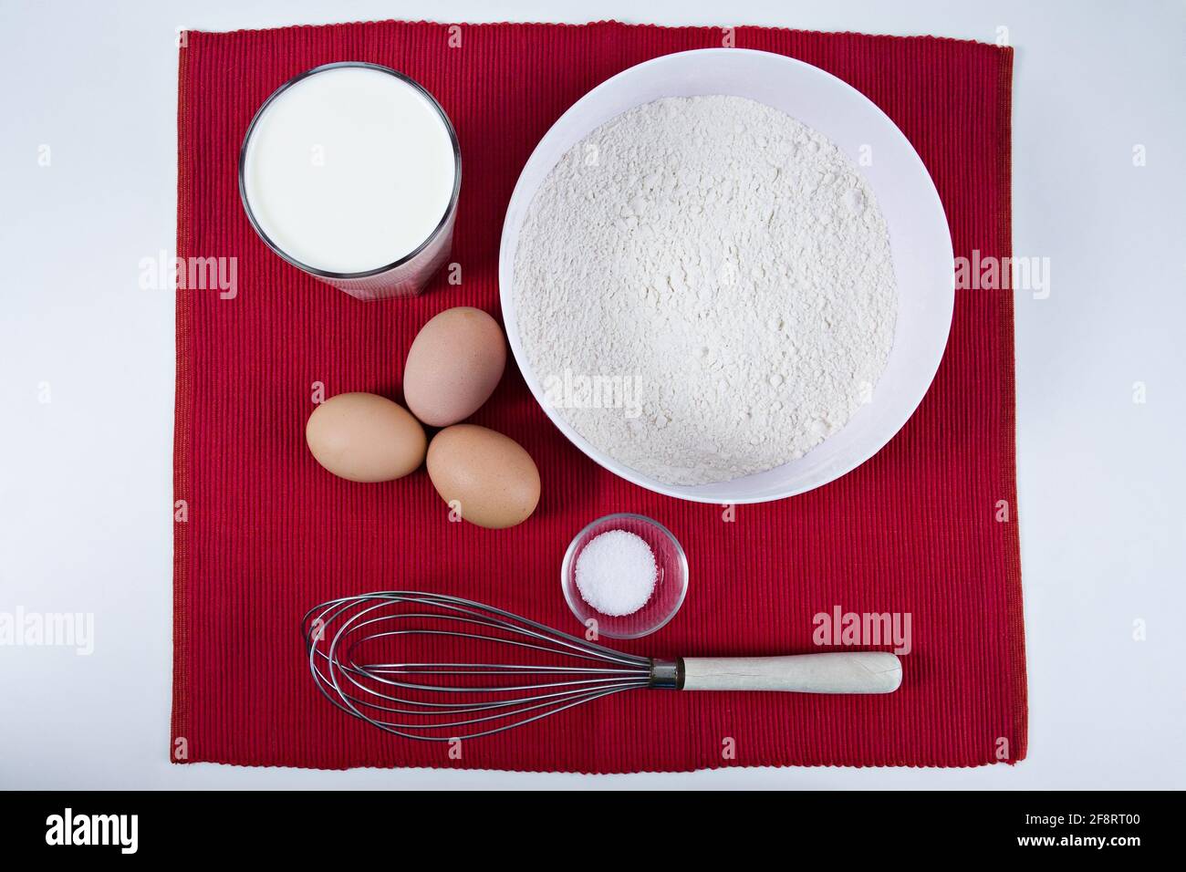 Zutaten für einen Pfannkuchenteig auf einer roten Matte Stockfoto