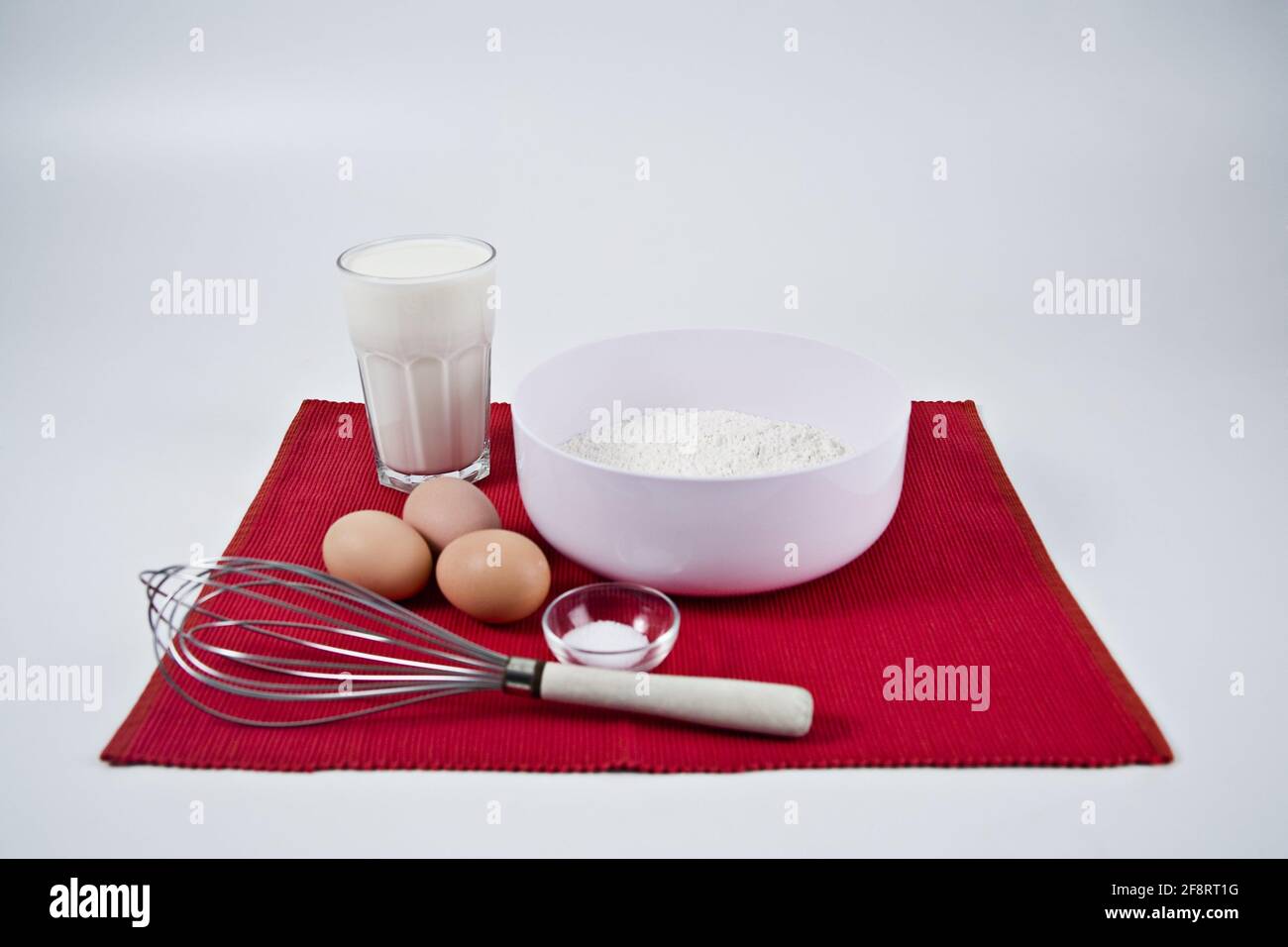 Zutaten für einen Pfannkuchenteig auf einer roten Matte Stockfoto