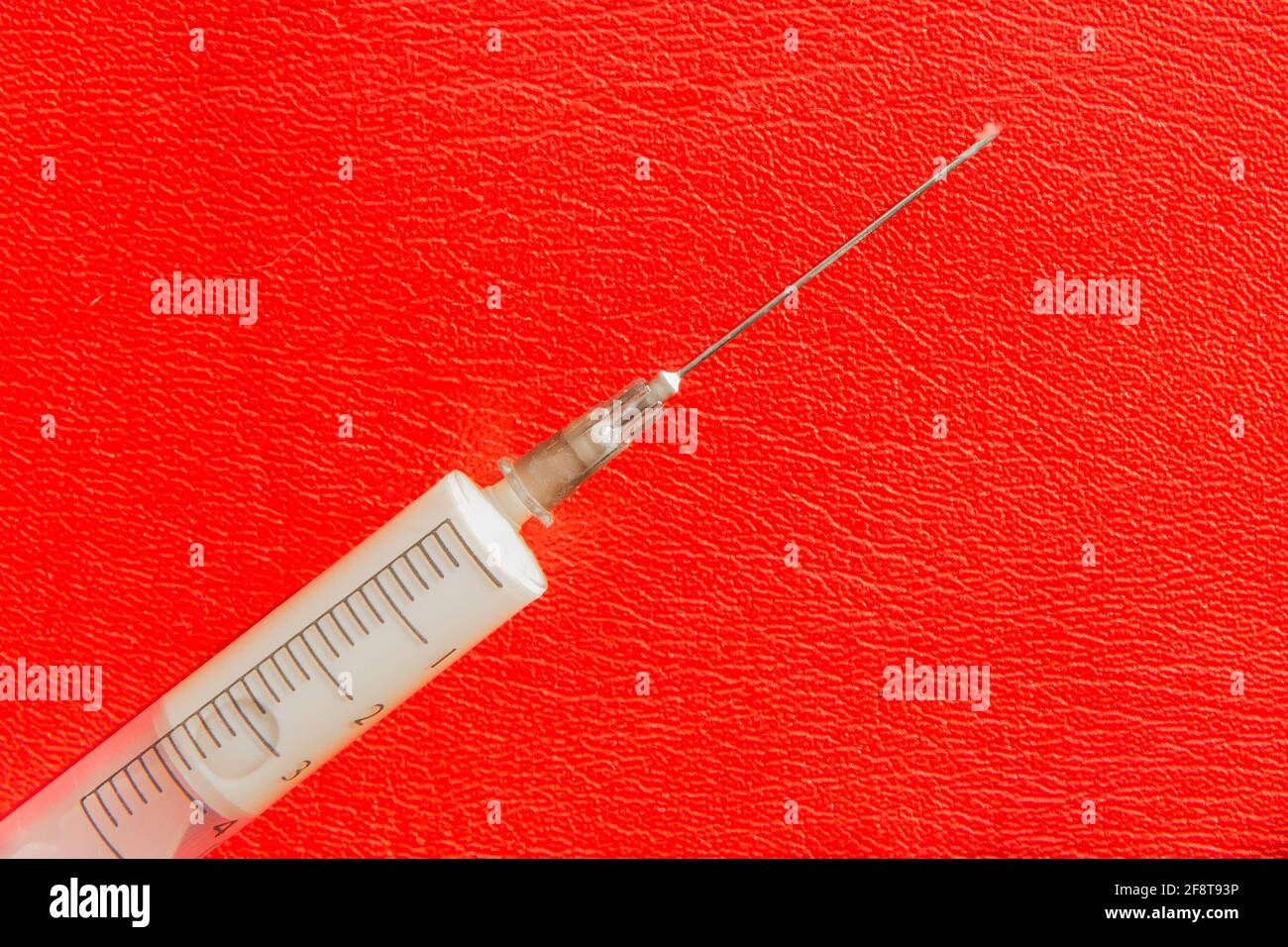Eine Spritze oder Injektion mit Medikamenten oder Medikamenten liegt auf einem roten Hintergrund. Suchtkonzept. Stockfoto