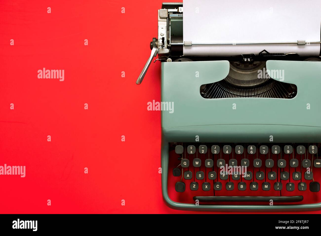Vintage Schreibmaschine mit weißem Papier isoliert mit Kopierplatz auf Ein roter Hintergrund Stockfoto