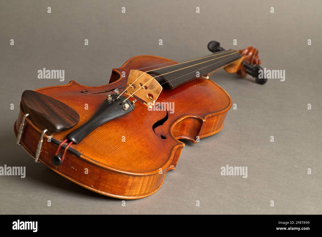 Deutschland. April 2021. Eine alte Geige mit leichten Kratzern und Beschädigungen, die auf einem neutralen, grauen Hintergrund liegt. Credit: dpa/Alamy Live News Stockfoto
