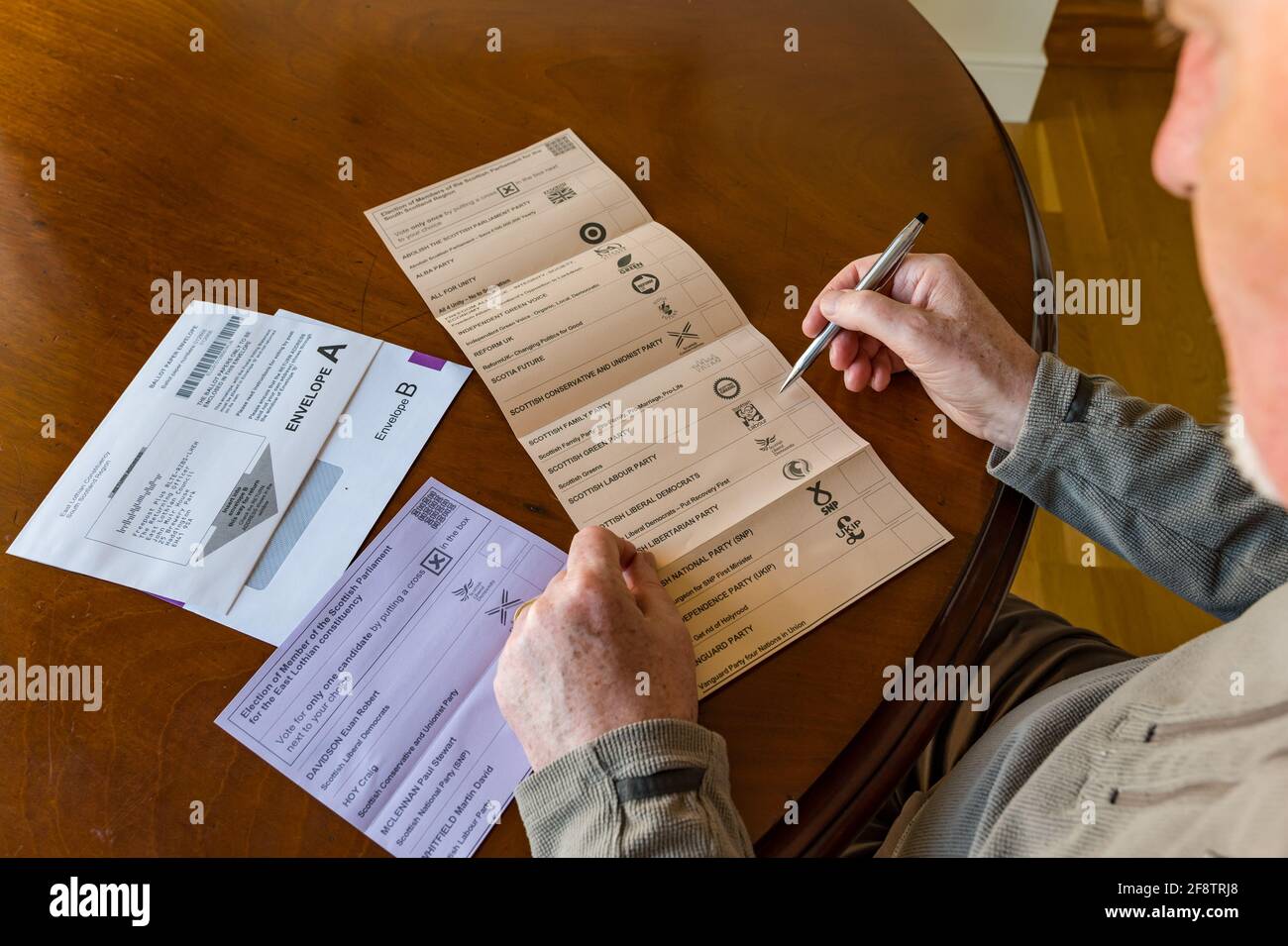 East Lothian, Schottland, Großbritannien, 15. April 2021. Für die schottischen Wahlen kommen Briefwahlen an: Die Bewohner des Bezirks können ihre Stimmen für die MSP East Lothian und die Region South of Scotland abgeben. Kandidaten für die ehemalige Partei sind Euan Davidson (Scottish Liberal Democrats), Craig Hoy (Scottish Conservative & Unionists), Paul McLennan (SNP) & Martin Whitfield (Scottish Labour & ehemaliger Abgeordneter, der 2019 an Kenny MacAskill, der für Alba steht, verloren hat). Die Regionalliste umfasst 16 Parteien. Ein Mann überlegt, für wen er auf dem Stimmzettel stimmen soll Stockfoto