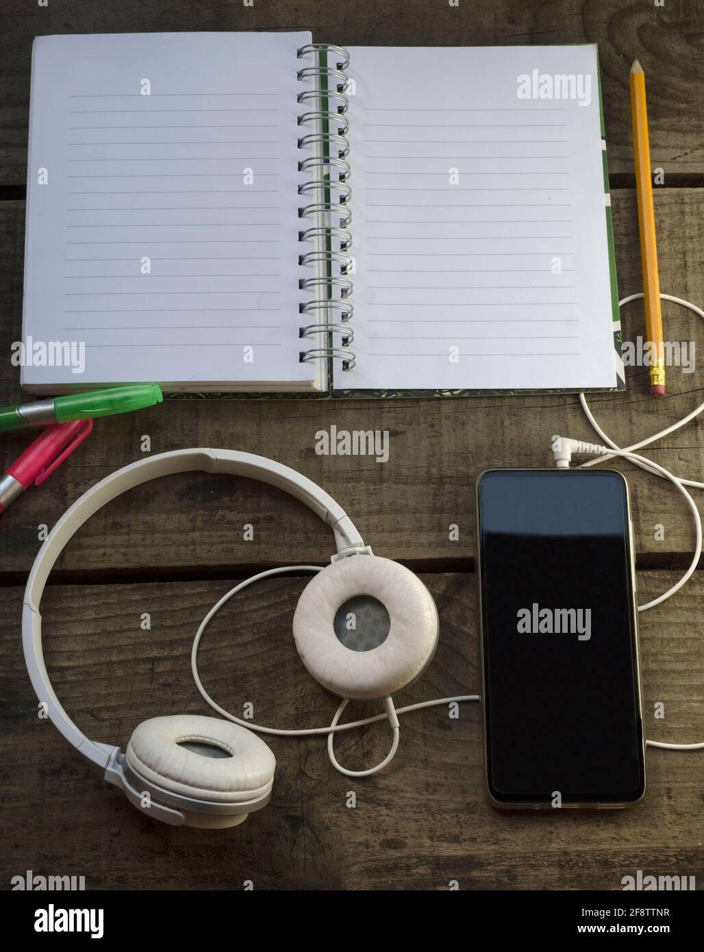 Cuadernocon lapiz y resaltadores, telefono para escuchar musicar e inspiarse, sobre mesa de madera Stockfoto