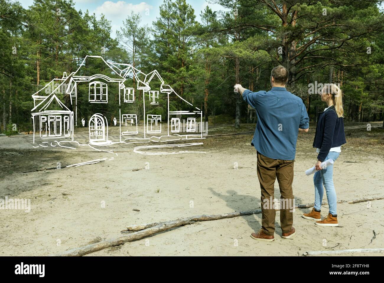 Junges Paar, das sich ihr Familienhaus im Wald ansieht Stockfoto