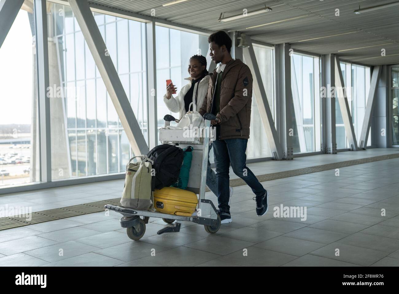 Glückliches afrikanisches Paar reist nach einer Coronavirus-Pandemie. Schwarze Passagiere im Flughafen mit Gepäck Stockfoto