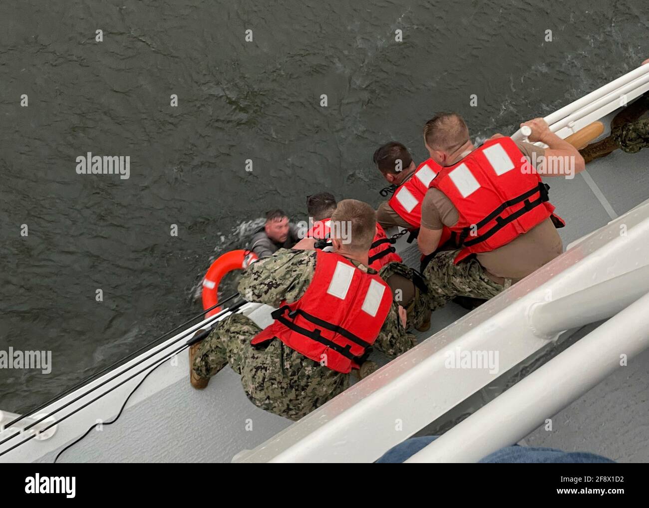 Die Besatzung des US-Küstenwache-Schneiters Glenn Harris zieht eine Person aus dem Wasser, nachdem das 175 Meter lange kommerzielle Liftboot Seacor Power im Golf von Mexiko am 13. April 2021, 8 Meilen südlich von Grand Isle, Louisiana, in stürmischer See gekentert ist. Die Küstenwache rettete sechs Menschen aus dem Öldienstschiff und 12 werden noch vermisst. Quelle: Planetpix/Alamy Live News Stockfoto