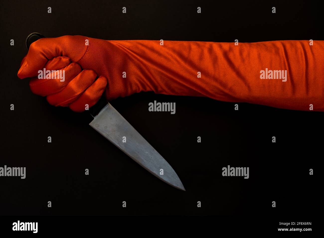 Weibliche Hand in rotem Handschuh mit einem Messer Stockfoto
