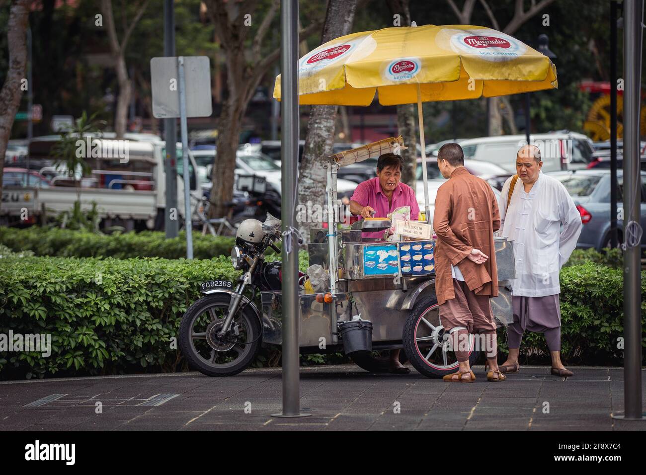 Singapur, Singapur - 4. Januar 2014: Zwei Mönche kaufen Eis-Sandwich von einem Straßenhändler. Stockfoto