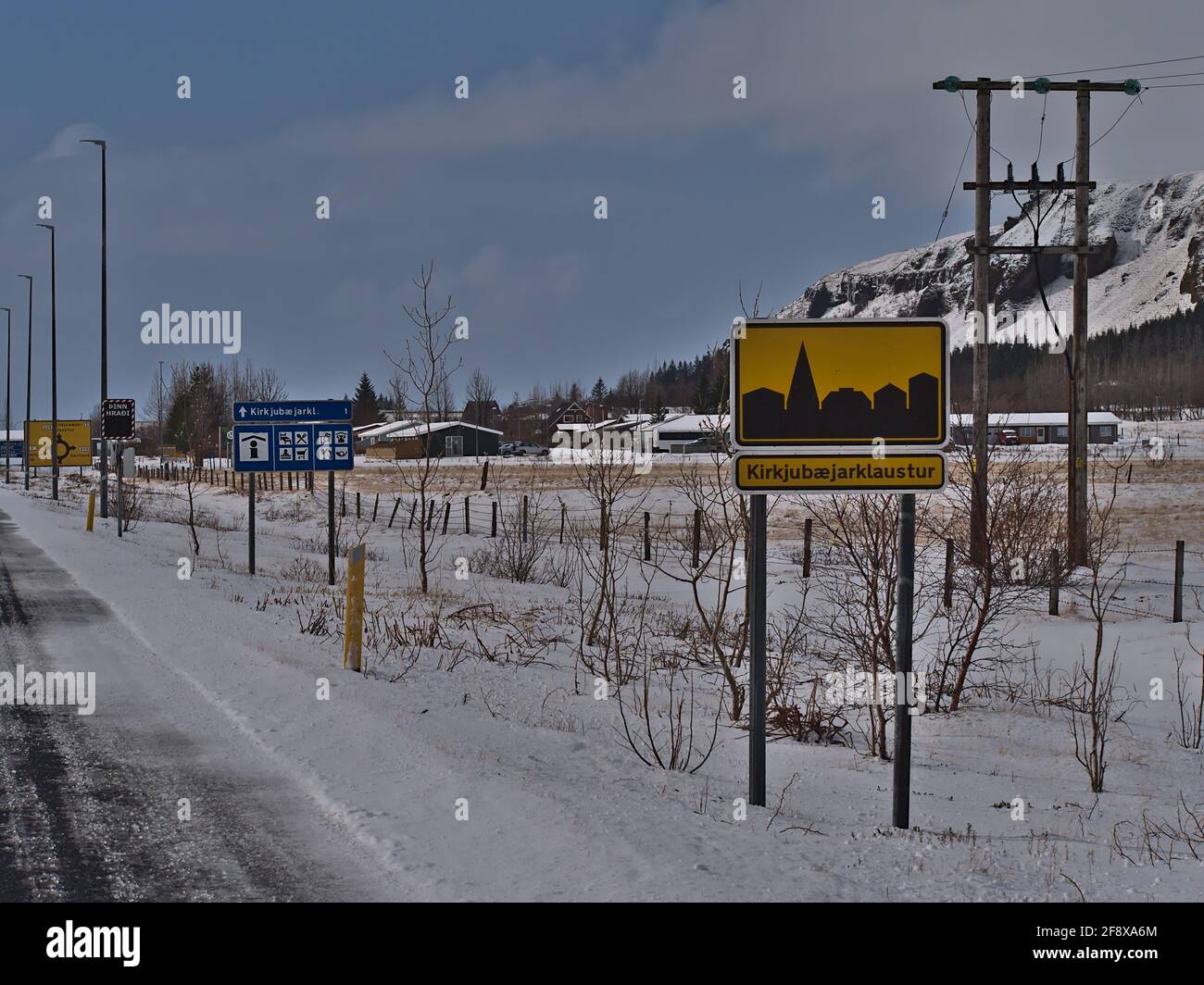 Blick auf den Dorfeingang der kleinen Stadt Kirkjubaejarklaustur im Süden Islands am sonnigen Wintertag mit gelbem Ortsnamen-Schild. Stockfoto