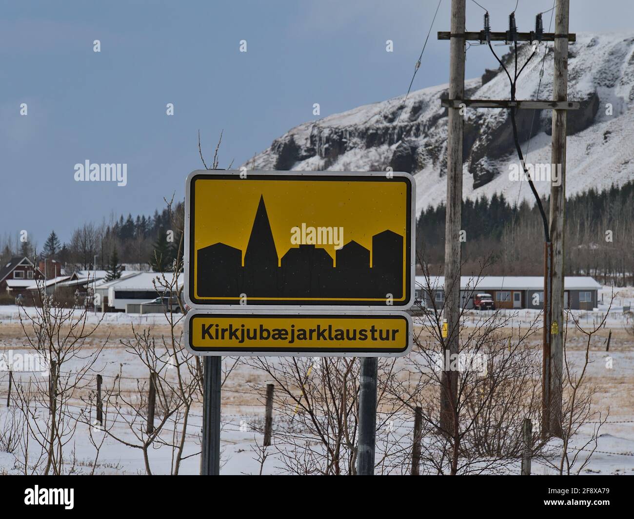 Nahaufnahme eines gelb gefärbten Stadtzeichens mit schwarzem Symbol des kleinen Dorfes Kirkjubaejarklaustur im Süden Islands am sonnigen Wintertag. Stockfoto