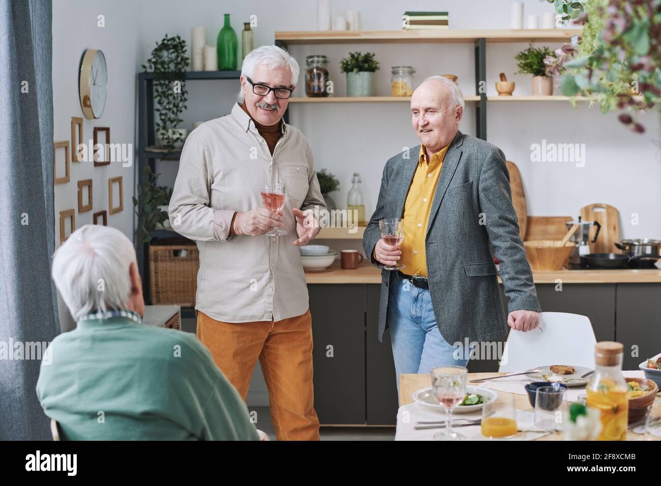 Gruppe älterer Männer, die Wein trinken und mit jedem sprechen Andere während des Abendessens zu Hause Stockfoto