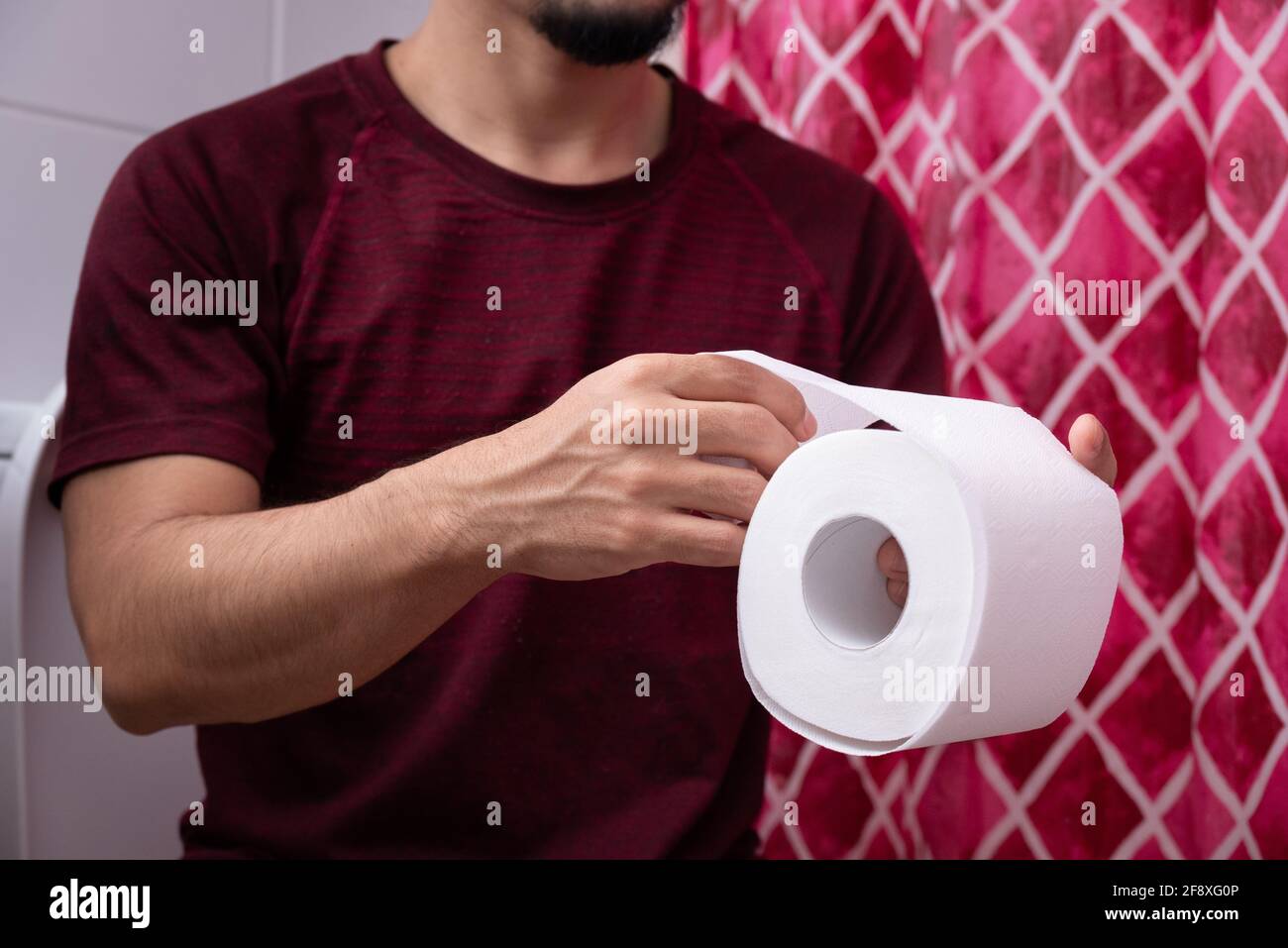 Nahaufnahme eines jungen lateinmanns, der die Toilette hält Papier im  Badezimmer Stockfotografie - Alamy