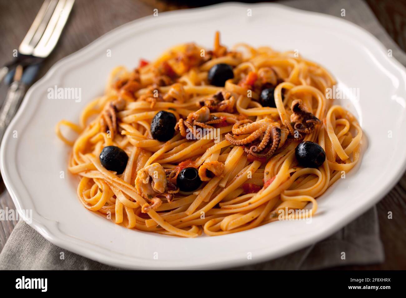 Pasta mit Oktopus und Oliven auf einem Teller. Stockfoto