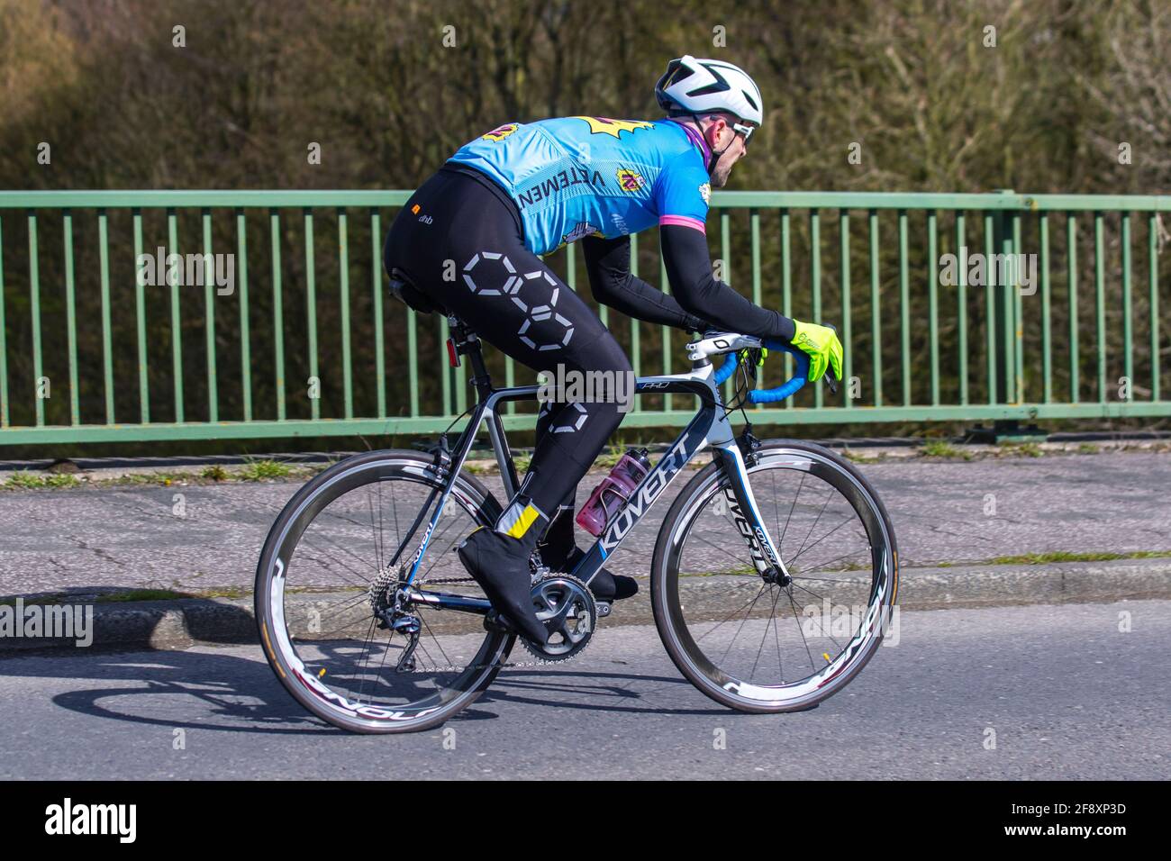 Männlicher Radfahrer, der auf dem Kovert FX-Pro-Sportstraßenrad auf der Landstraße über die Autobahnbrücke im ländlichen Lancashire, Großbritannien, fährt Stockfoto