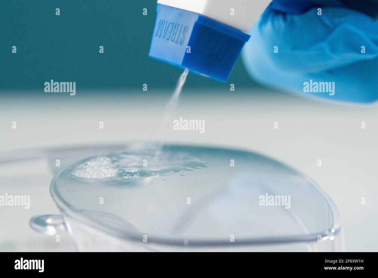 Makro-Nahaufnahme einer Sprühflasche, die antiseptisch auf ein mit Kunststoff verunreinigtes Produkt sprüht. Stockfoto